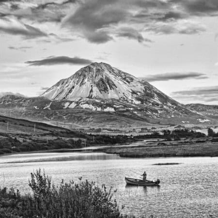 black and white photograph of Errigal mountain with a fishing boat in the lake