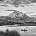 black and white photograph of Errigal with a fishing boat in the lake in the foregorund